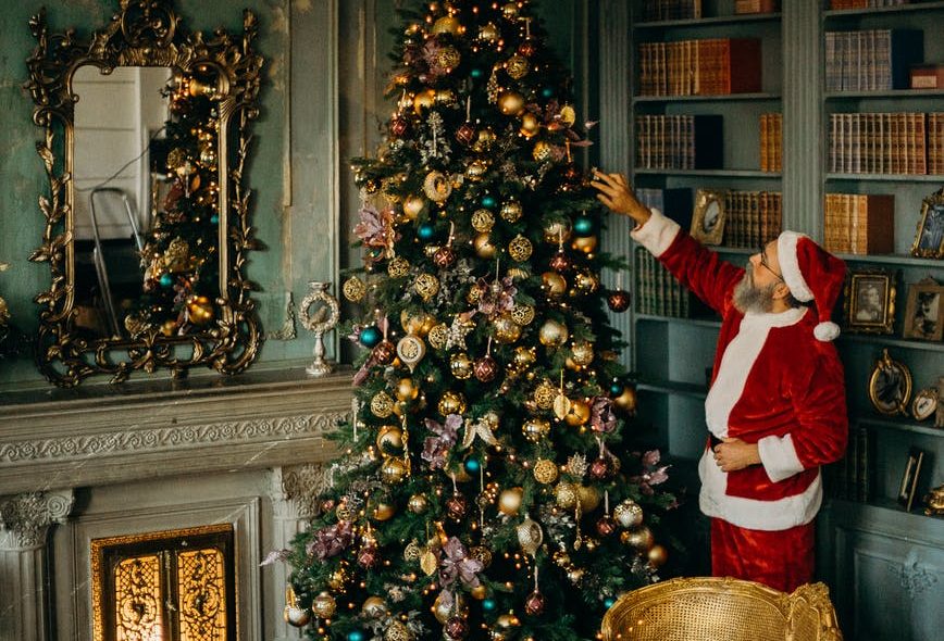 man standing beside christmas tree